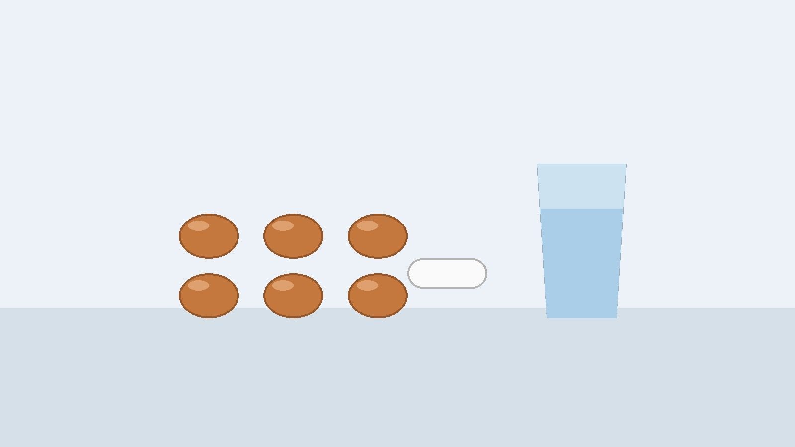 Six round orange-brown tablets in two rows, one white caplet and a glass of water on a table